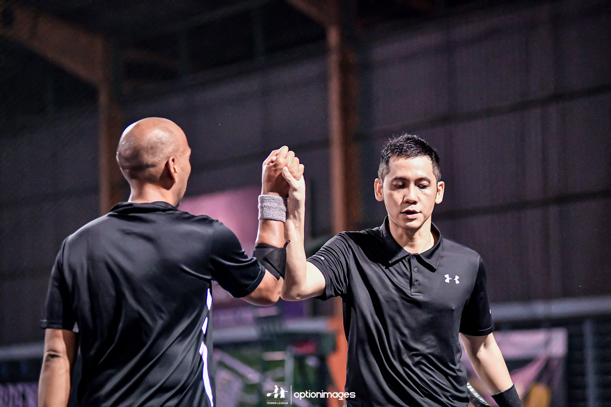 Doubles partners clasping hands on court during the beginner doubles final.