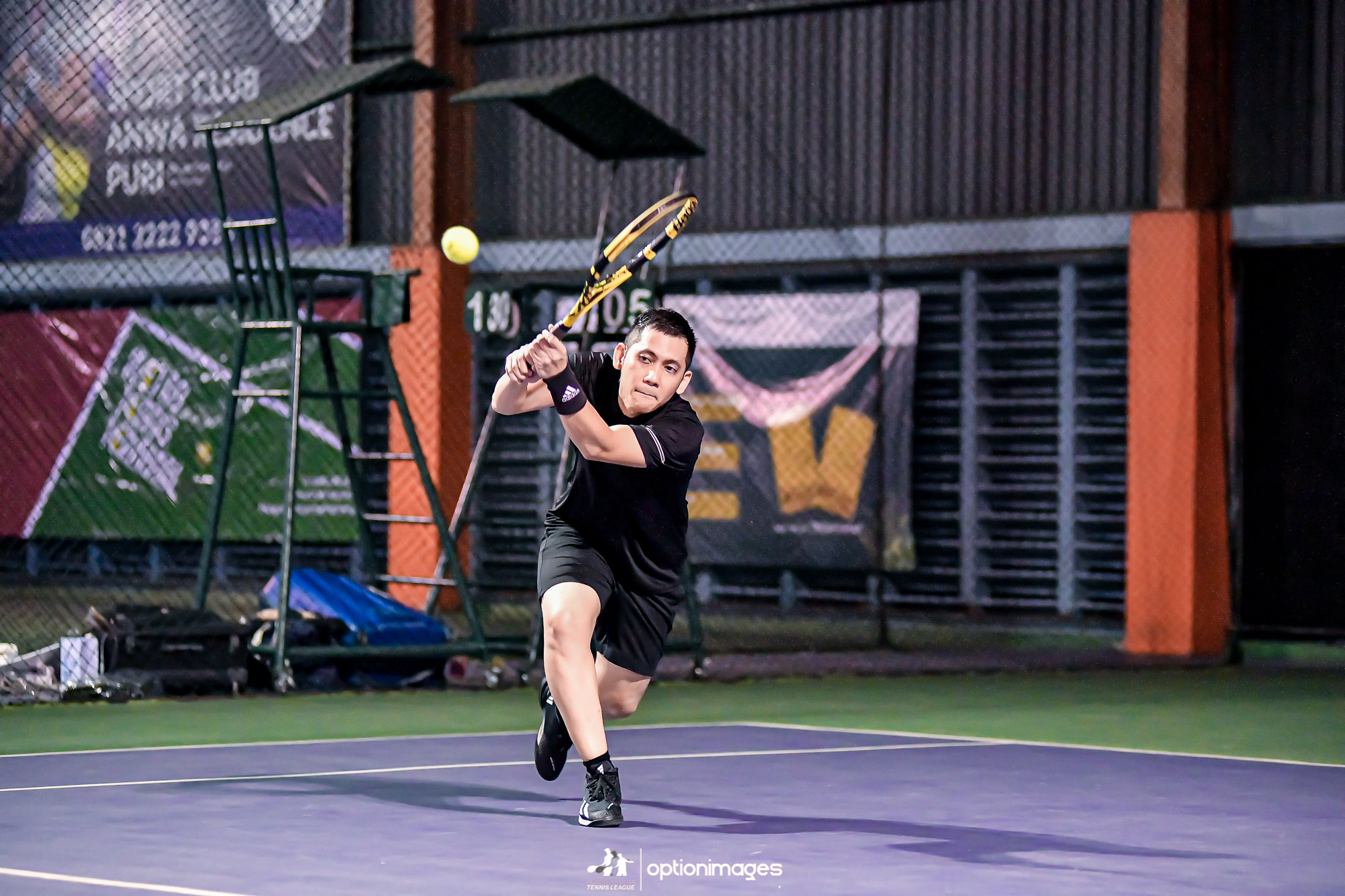 A player in black hitting a two-handed backhand during the beginner doubles final.