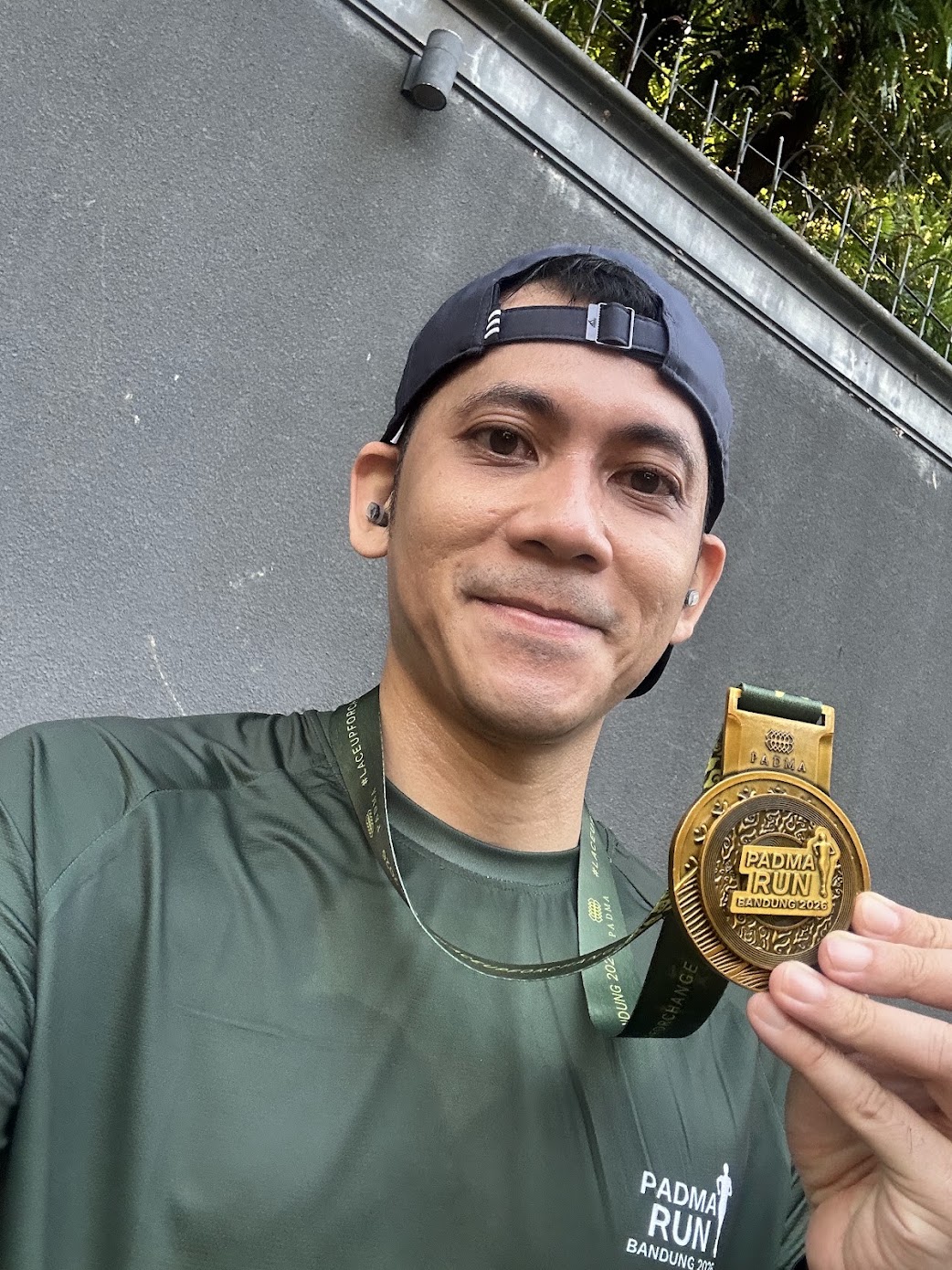 A smiling runner holding a Padma Run Bandung 2026 finisher medal.